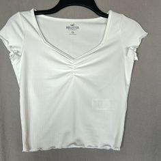 Hollister White Tee - Brand New Without Tags!! V-Neck Ruched Chest Lettuce Edge On Sleeve And Bottom Hem. Ribbed Detail Soft Material 88% Polyester / 12% Elastane Size: Xs Color: White Condition: Brand New!! Never Worn Or Washed. Casual White Fitted V-neck Top, Casual White Stretch V-neck Top, Ribbed V-neck T-shirt For Summer, White Fitted Top V-neck T-shirt, White Fitted V-neck T-shirt, Casual Ribbed V-neck Top, Casual Fitted White V-neck Top, Casual Fitted V-neck Top, Clothing Pieces