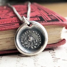 "This sterling silver wax seal pendant features a butterfly resting upon a rose surrounded by the romantic French phrase \"La Douceur M'Attire\" which translates to \"Sweetness Attracts Me\". Love is a delicate dance of the sweetness of two people. Everything in nature lives in an ever-moving connectedness. A plant cannot flourish without water. A butterfly cannot flutter without the sweet nectar of a flower. Humans need to feel this connection to survive. This necklace is a promise of your love Silver Birth Flower Necklace For Anniversary, Silver Birth Flower Necklace For Anniversary Gift, Elegant Stamped Flower Pendant Necklace, Elegant Stamped Flower Pendant Necklaces, Elegant Memorial Jewelry With Flower Charm, Elegant Hand Stamped Medallion Jewelry, Elegant Stamped Jewelry For Memorial, Elegant Hand Stamped Jewelry For Memorial, Elegant Hand Stamped Jewelry For Memorials