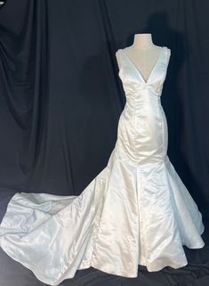 a white wedding dress on display in front of a black backdrop