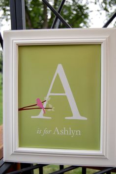 a white frame with a pink bird sitting on top of it and the letter a is for ashyn