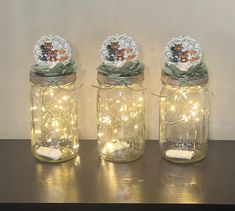 three mason jars with lights and teddy bears in them on a counter top next to each other