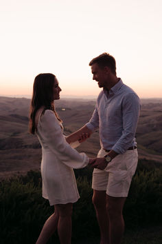 a man and woman standing next to each other holding hands