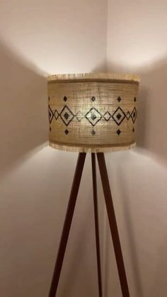 a lamp that is on top of a wooden tripod stand in a room with white walls