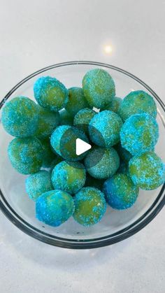 a glass bowl filled with blue and green donuts on top of a white counter