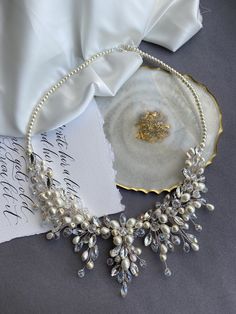 a necklace with pearls on it sitting next to a piece of paper