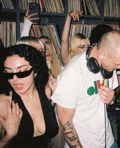 a man standing next to a woman with headphones on in front of a record player