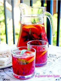 the pitcher and two glasses are on the table next to each other with fruit in them