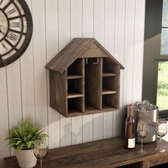 a wooden shelf with a wine bottle and glass on it next to a wall clock