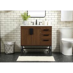 a white toilet sitting next to a wooden cabinet in a bathroom with black tile on the walls