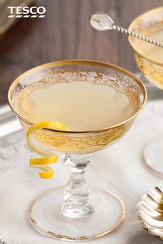 two glasses filled with yellow liquid and garnished with lemon wedges on a table