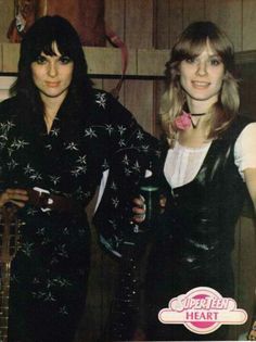 two women dressed in black and white posing for a photo with one holding a guitar