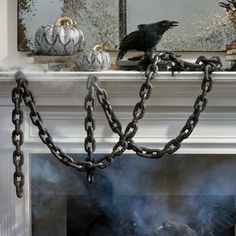 a black bird sitting on top of a fire place with chains hanging from it's sides