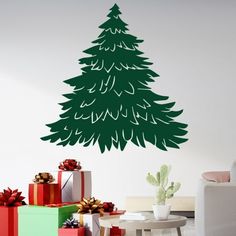 a christmas tree with presents in front of it and a wall decal behind it