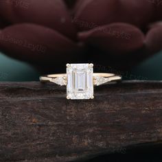 an emerald cut diamond engagement ring on top of a piece of wood