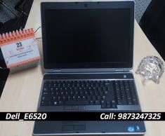 an open laptop computer sitting on top of a wooden desk next to a notepad