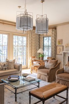 a living room with couches, chairs and tables in front of two large windows