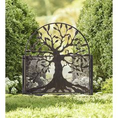 an iron gate with a tree on it in the middle of some bushes and trees