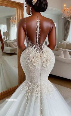 the back of a woman's wedding dress with flowers on it, in front of a mirror