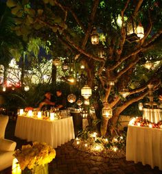 an outdoor dining area is lit up with candles and flowers in vases on the tables