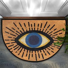 a door mat with an eye on it and plants in the corner next to it