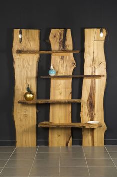 a wooden shelf with two vases sitting on top of it next to a black wall