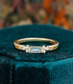 an emerald colored diamond ring sits on top of a velvet box