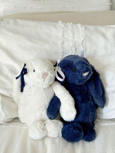 two stuffed animals sitting on top of a bed