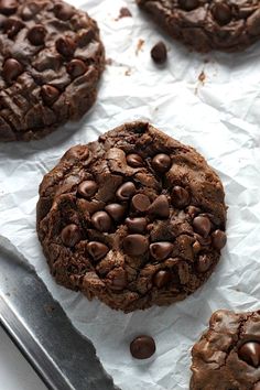 several chocolate cookies are on top of white paper and one cookie has been cut in half