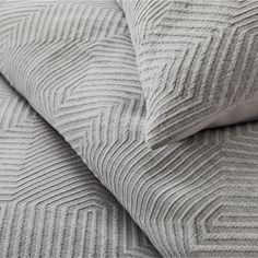 a close up view of the textured bedding and pillows on a white bed