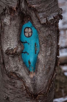 a tree with a blue face painted on it's trunk and the bark is peeling