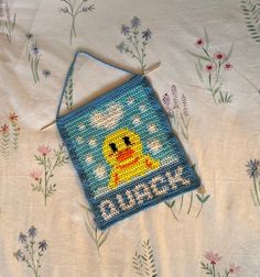 a cross - stitched bag with a ducky on it sitting on a bed