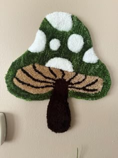 a green and white mushroom shaped rug hanging on the wall next to a light switch