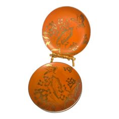 two orange plates with designs on them sitting side by side in front of a white background