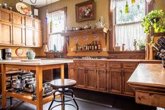 a kitchen with wooden cabinets and stools next to a counter top in front of a window