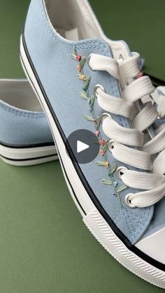 a pair of blue tennis shoes with embroidered flowers on them