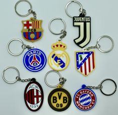 a bunch of different key chains that are shaped like soccer teams and numbers on them