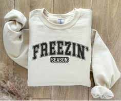 Holiday Order Deadline - December 10th. Stay Cozy and Warm with the Freezin' Season Sweatshirt - Your Go-To Winter Sweatshirt! Embrace the cold in style with our Freezin' Season Sweatshirt! This cozy winter sweatshirt is perfect for those chilly days when you want to stay comfortable and warm, whether you're braving the cold outdoors or lounging inside. The cozy winter sweatshirt is designed for anyone who loves the winter season and needs a go-to piece for those sweater-weather days. Crafted fr Casual Crew Neck Sweatshirt For Cold Weather, Cozy Crew Neck Tops For Cold Weather, Cotton Sweatshirt For Cold Weather In Fall, Cozy Fit Cotton Sweatshirt For Cold Weather, Cotton Crew Neck Top For Cold Weather, Cozy Cotton Sweatshirt For Cold Weather, Cotton Crew Neck Sweatshirt For Cold Weather, Relaxed Fit Sweatshirt For College In Winter, Cozy Sweatshirt With Ribbed Cuffs For Cold Weather