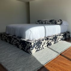 a bed sitting on top of a wooden floor next to a white and black blanket