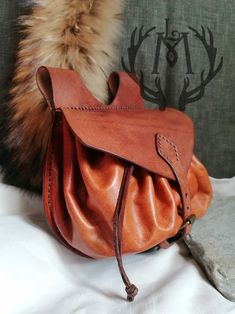 a brown purse sitting on top of a bed next to a fur covered headboard