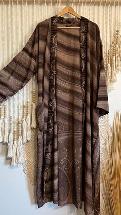 Our original silhouette - the Sari Silk Kimono in our signature long-length. Perfect for the free-spirited hippy or flower child in all of us, this beautiful kimono boasts a one-of-a-kind print, made from the finest quality silk for a luxurious and comfortable fit. 𖤓 Features full-length sleeves and removable matching sash. 𖤓 Long-length. 𖤓 External pockets. 𖤓 100% recycled sari silk, ethically made in India. SILK TEXTURE: Silk Blend Please refer to our Silk Guide for descriptions on each ty Flowy Boho Print Kimono For Fall, Fall Boho Print Open Front Kimono, Fall Boho Print Flowy Kimono, Bohemian Long Patterned Kimono, Bohemian Long Printed Kimono, Long Bohemian Printed Kimono, Long Fall Kimono With Relaxed Fit, Long Hippie Kaftan For Spring, Flowy Long Kimono For Festival