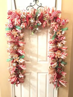 a christmas wreath hanging on the front door decorated with candy canes and bows,