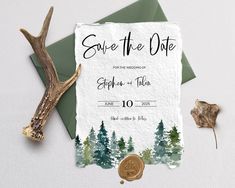 save the date card with antlers and trees on it next to a green envelope