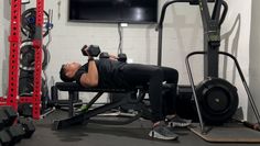 a man laying on top of a bench in front of a tv and gym equipment