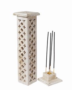 a candle holder with three candles and two sticks in it next to each other on a white background