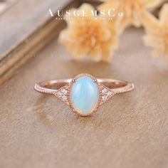 an opalite and diamond ring sits on a wooden surface next to some flowers