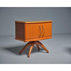 an orange cabinet sitting on top of a wooden tripod base with two handles and one door open