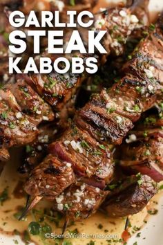 grilled steak kabobs on a white plate with garnish