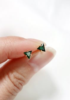 Tiny triangle stud earrings - in a deep emerald green.  Hand set faceted cubic zirconia. Sold as a SINGLE (choose options above).  PAIRS available here: https://www.etsy.com/listing/772226804/Hardware has been tumble polished for hours to achieve a satin finish, butterfly backings.  Packaged in a beautiful gift box.Perfect for standard lobe piercings and small enough to be great stacking pieces for 2nd and 3rd piercings.Paired with the micro star studs worn at the 2nd piercing available here: ht Single Stone Studs Gold, Single Stone Earrings Gold, 3rd Piercings, Single Stone Earrings, 2nd Piercing, Dainty Earrings Studs, Green Stone Earrings, Triangle Stud Earrings, Lobe Piercings