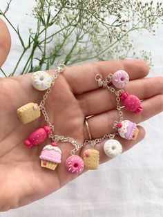 a hand holding a charm bracelet with donuts and doughnuts on it's chain