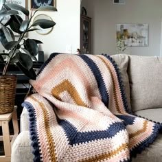 a couch with a blanket on it next to a potted plant